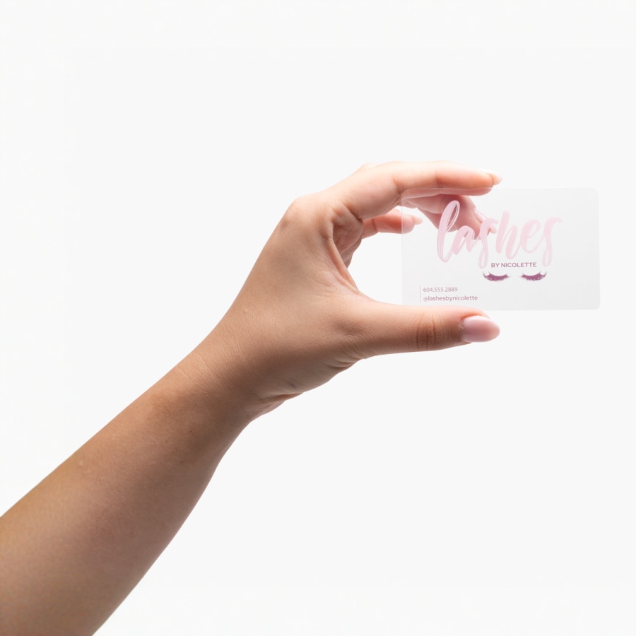 A person holding a clear plastic business card promoting an eyelash esthetician.