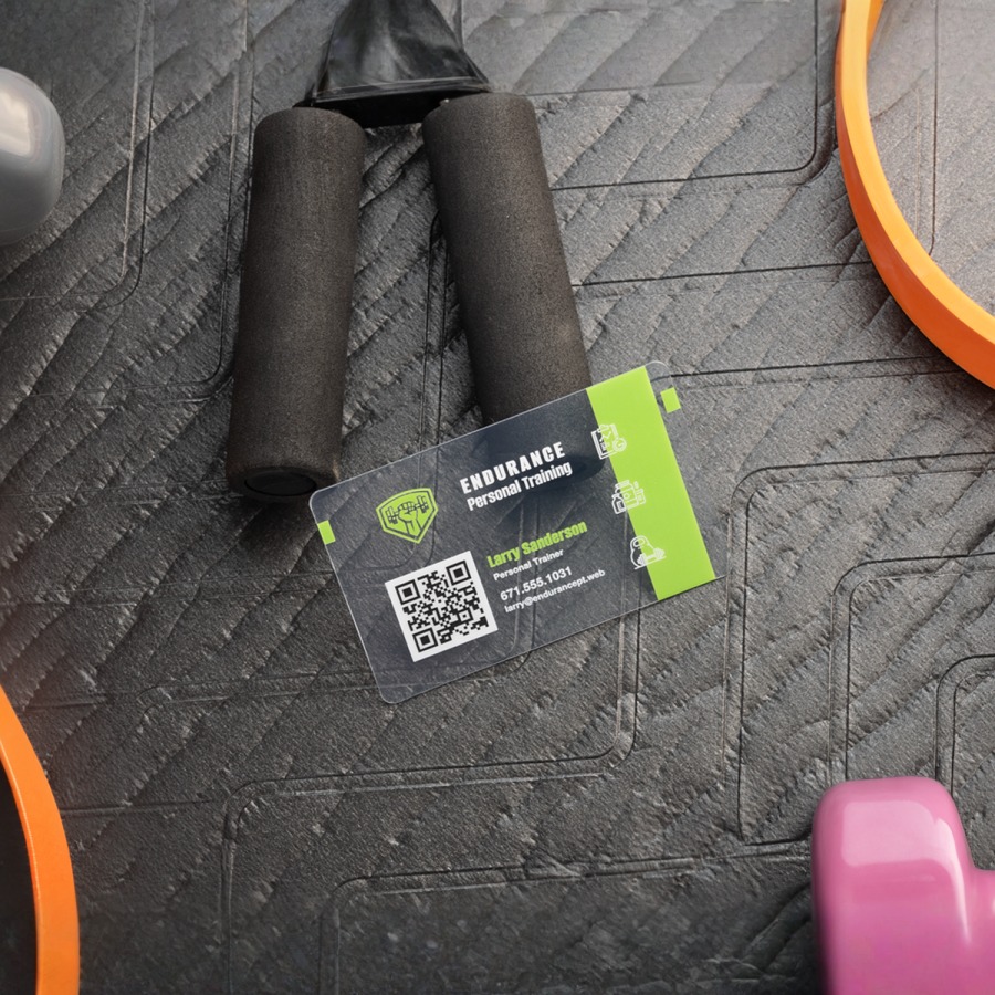 A clear plastic business card for a personal trainer, with exercise equipment in the background.