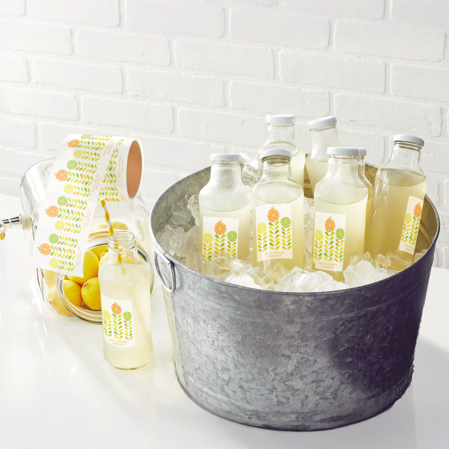 An ice bucket filled with bottles featuring waterproof labels, next to a roll of waterproof labels.