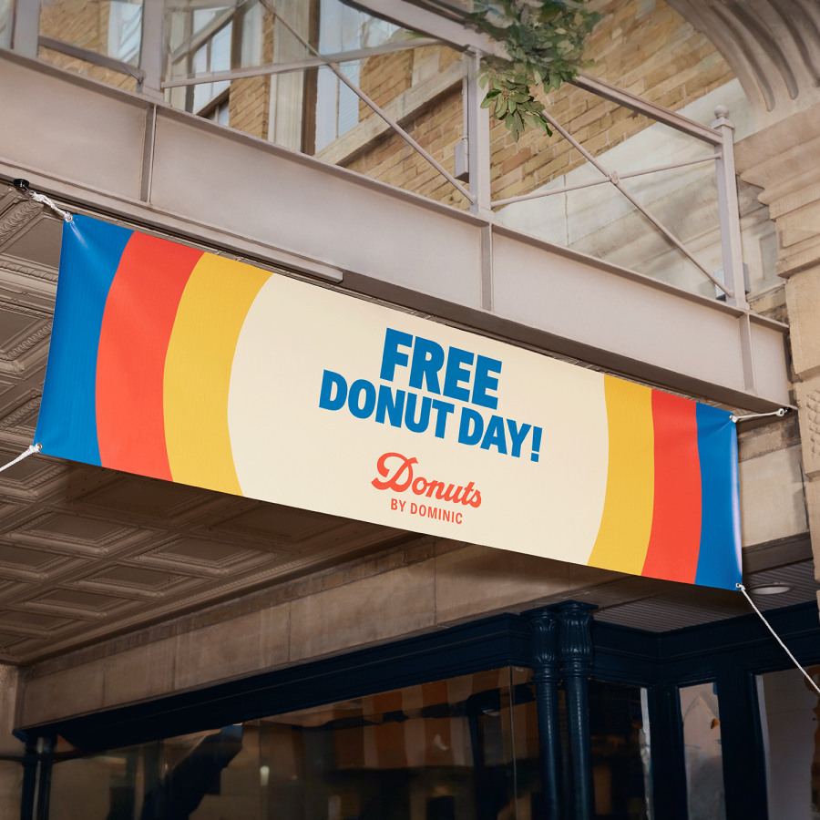 A colorful hanging vinyl banner promoting free donuts.