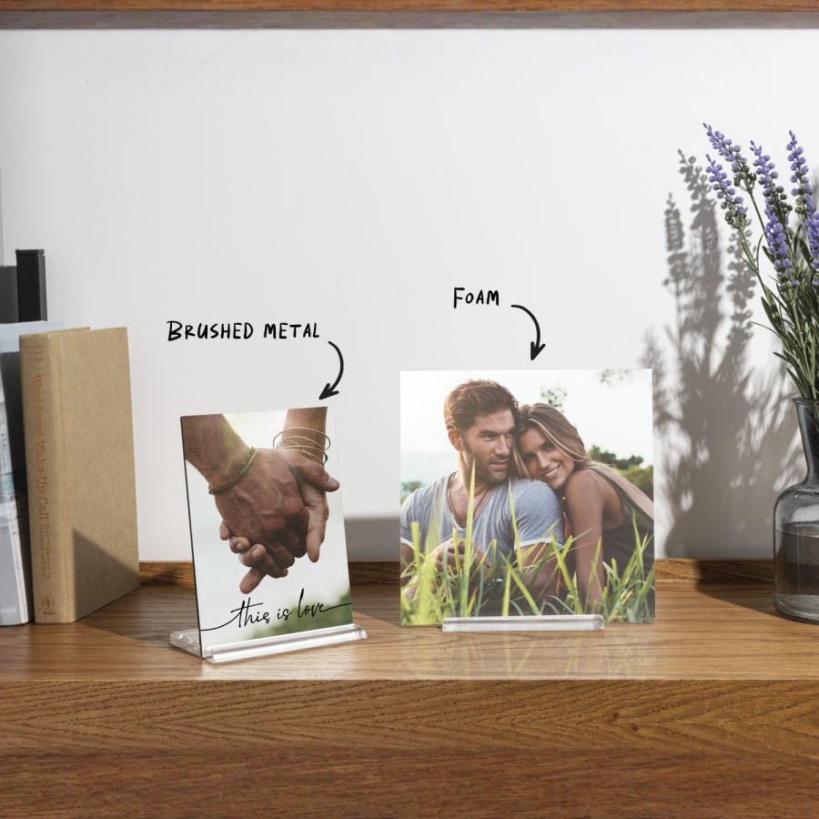 Two custom photo tiles displayed on a wooden tabletop, with notes that one is made of brushed metal and the other is made of foam board. 