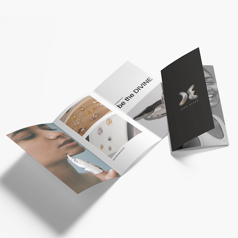Tri-fold brochures for a jewelry brand, one open and one partially closed, displayed on a white surface.