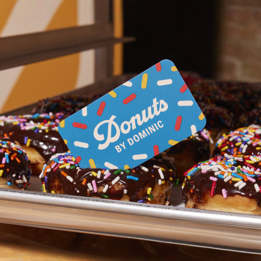 A playful blue business card resting on a tray of donuts.