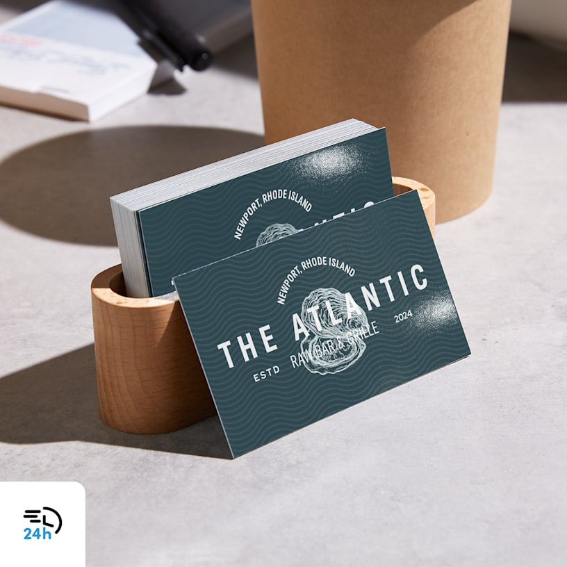 A stack of business cards from a restaurant in a card holder, with a 24-hour delivery icon in the corner.
