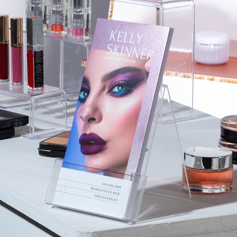 Glittery purple foil accent rack cards from a make up artist being displayed on the counter of a beauty salon.