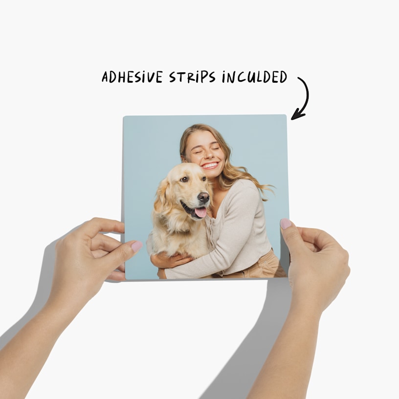 A pair of hands holding a photo tile printed with a picture of a woman embracing a Golden Retriever.  