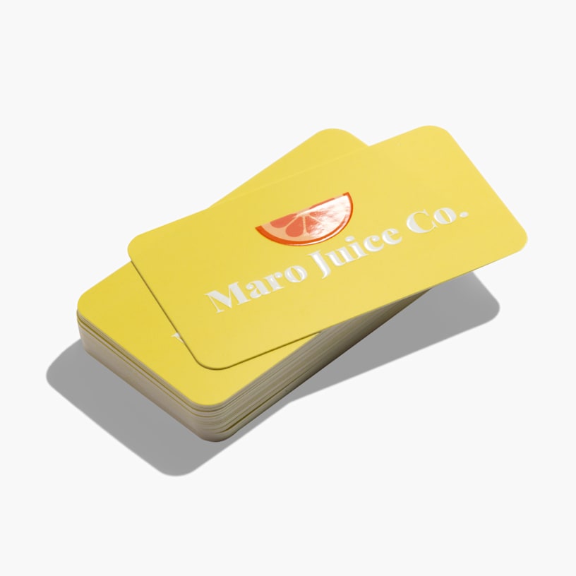 A stack of yellow business cards from a juice company, with embossed gloss foil used for the name and logo.
