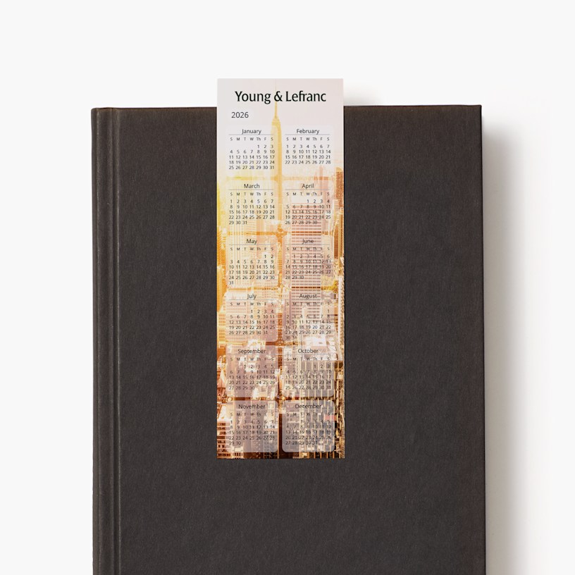 A 2026 calendar bookmark for an agency resting on a closed black book.