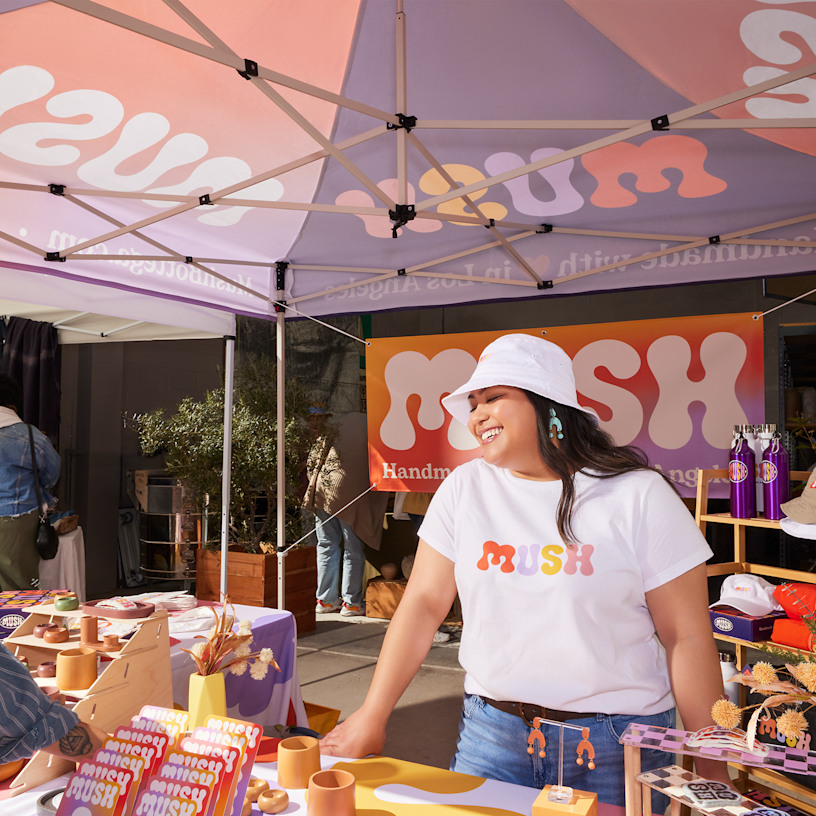A close up of a handmade goods store set up underneath a canopy tent in an outdoor market.
