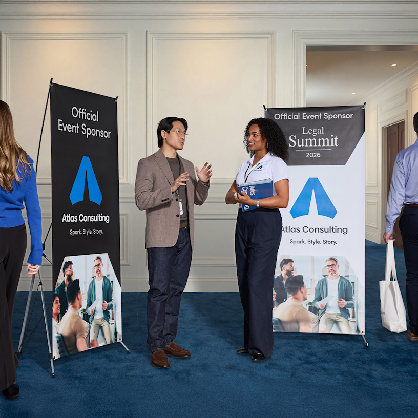  A man and a woman in front of 2 consulting X-banners at a trade show.