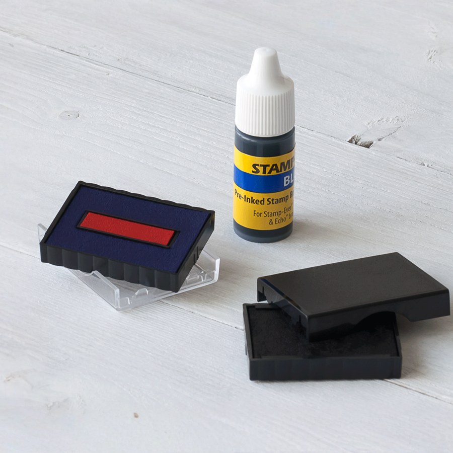 A red stamp pad outside of its case alongside a bottle of blue refill ink.