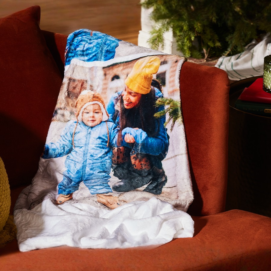 Personalised photo blanket lying on the sofa, showing a mum and her toddler on winter holidays.