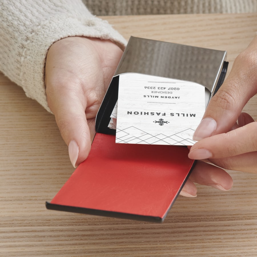 A woman is removing a card from a black leather vertical business card holder.