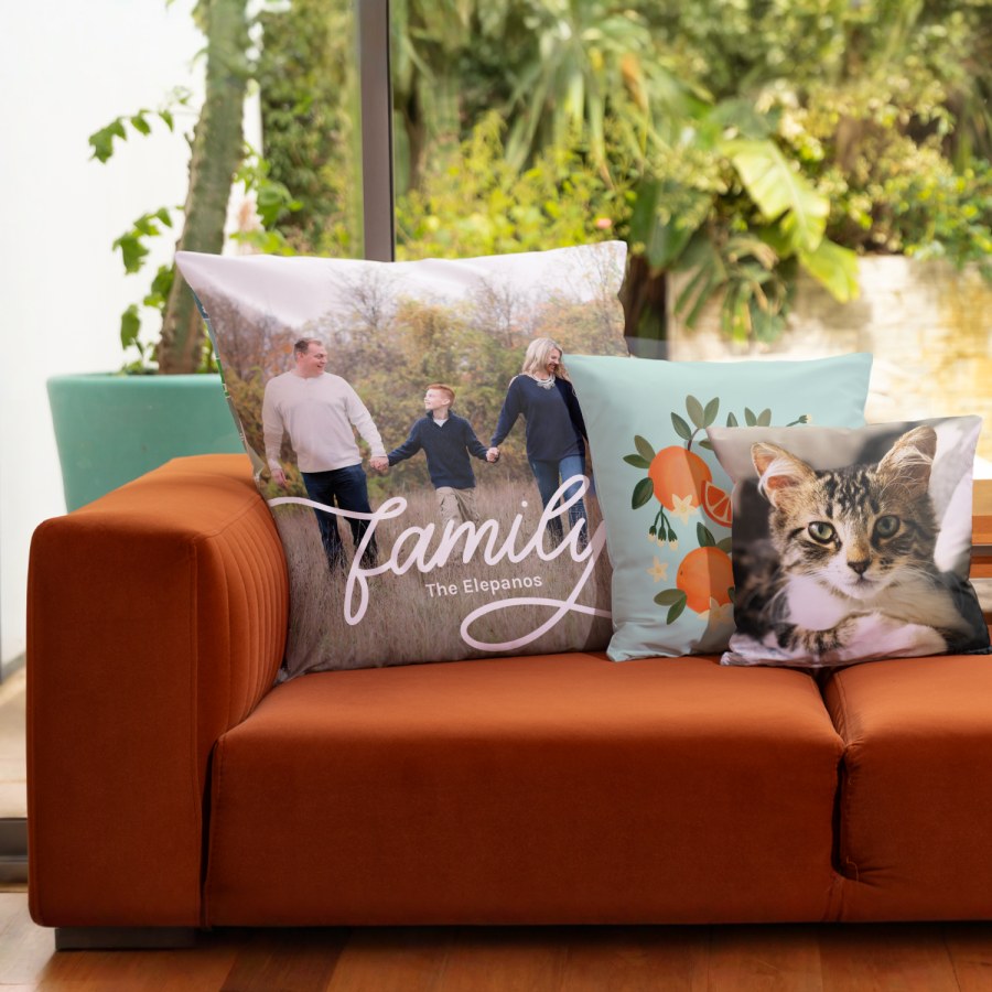 Three personalised photo cushions on a rust coloured sofa featuring a family photo cushion a floral printed cushion and a custom pillow with a cat picture