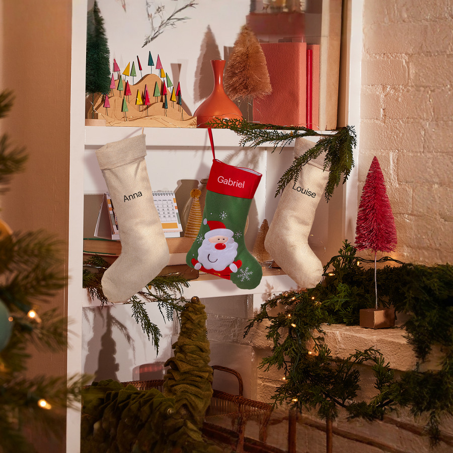 Custom Christmas stockings hanging on festive shelves, including red Santa stocking and personalised burlap designs with names.