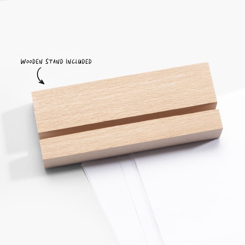 A wooden stand with a slit made to fit a tabletop print, with a note that says the wooden stand is included. 