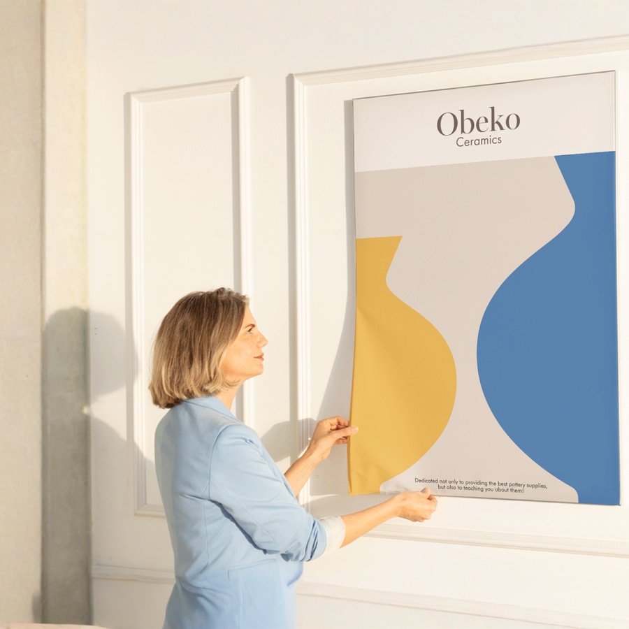 A woman tucking a new fabric print for a ceramics company into its seamless frame.
