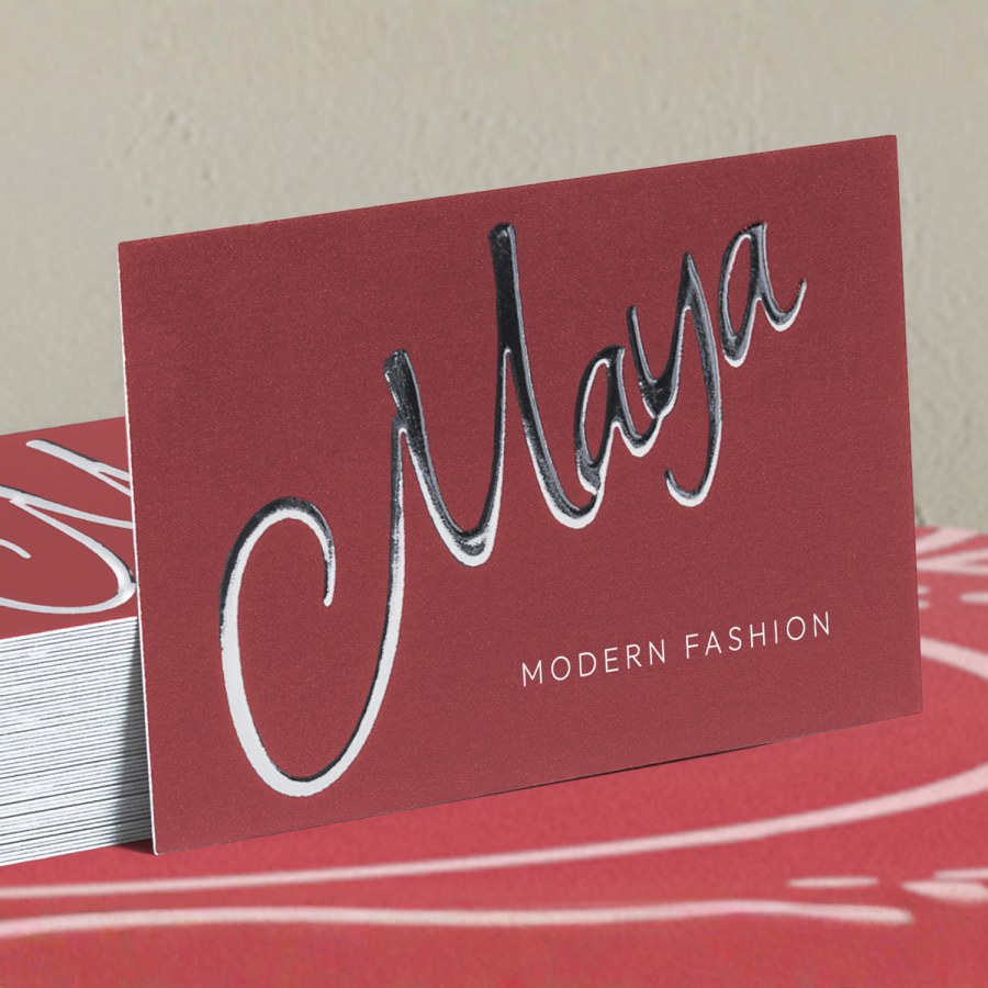 A stack of business cards for a retail shop, made of raised silver foil.