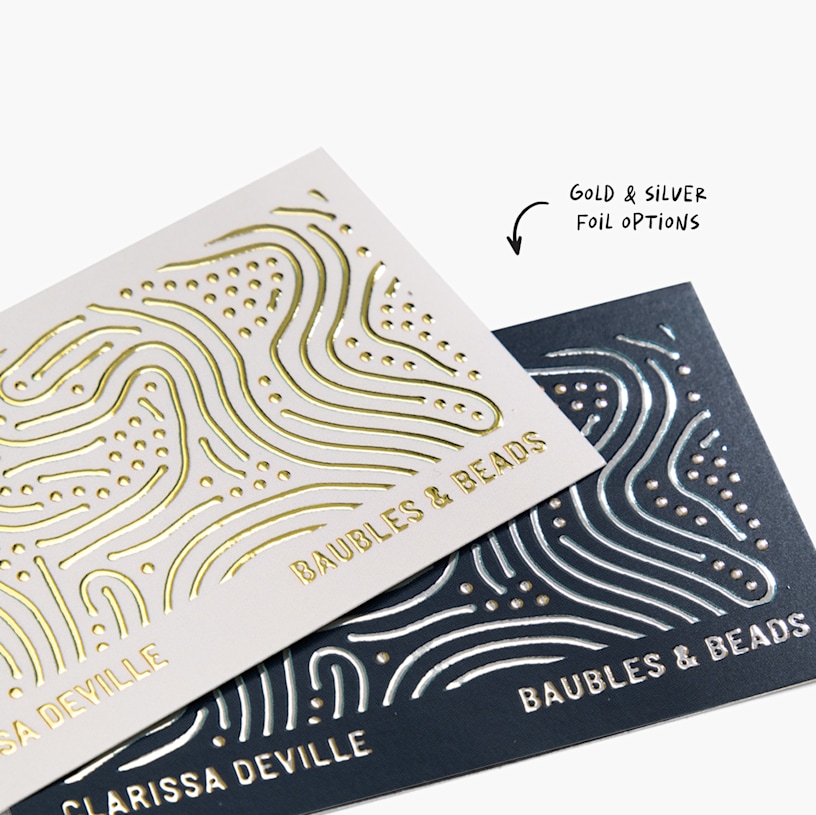 Two standard business cards with different metallic foil designs for the same person, with a note highlighting the gold and silver foil options.