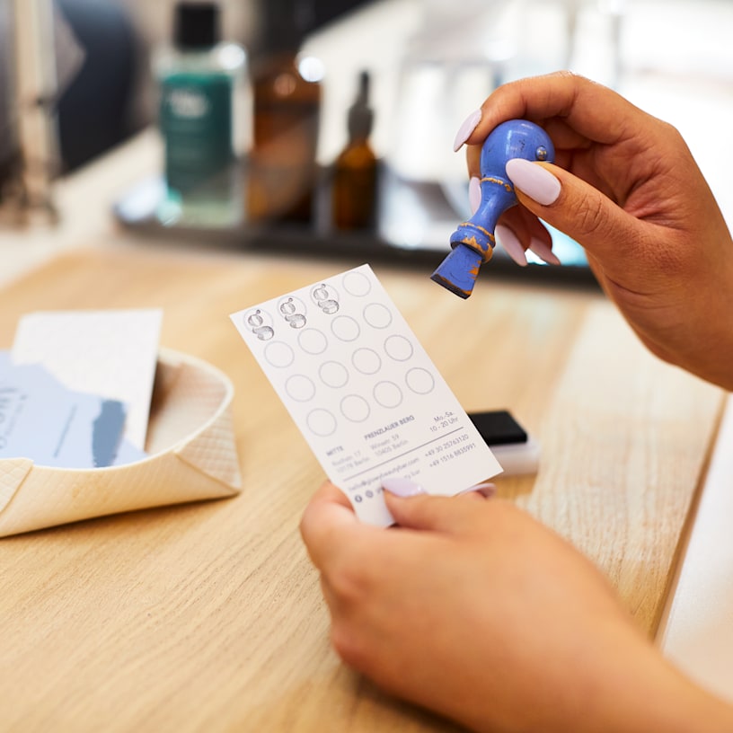 A hand poised to stamp a loyalty card.