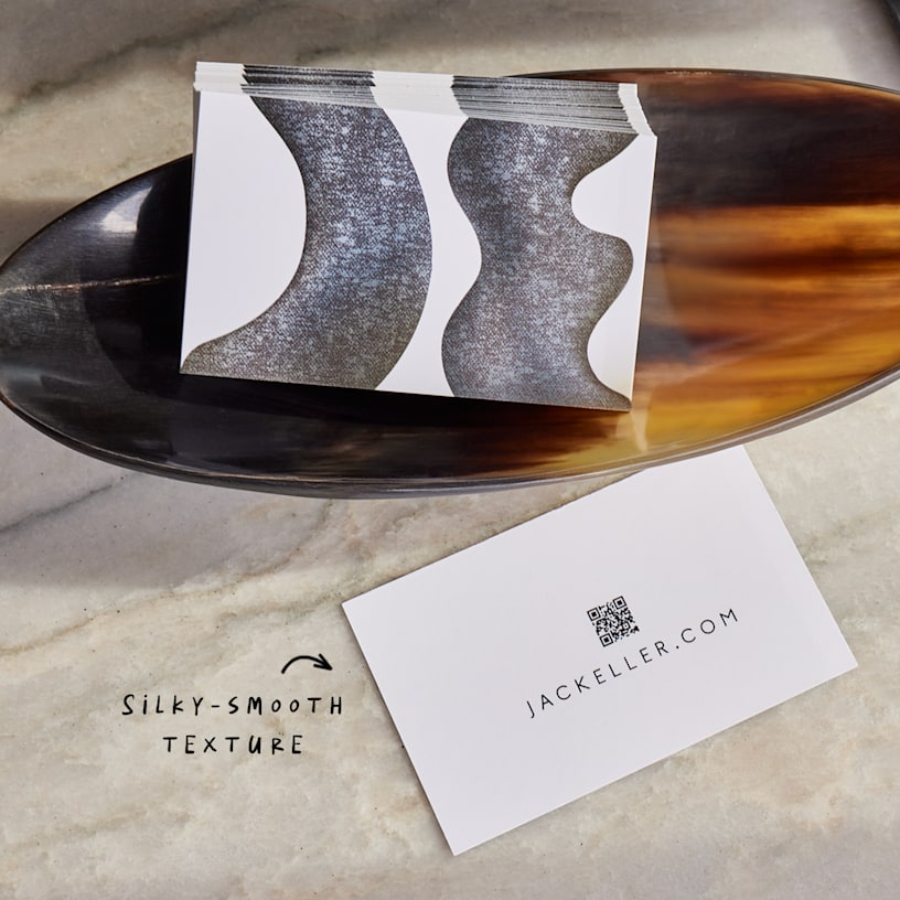 A stack of matte business cards resting in a wooden bowl, with a note highlighting their silky-smooth texture.