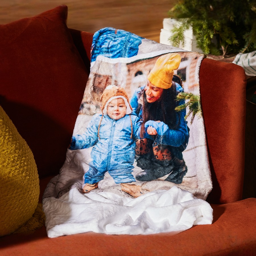 Personalised photo blanket lying on the sofa, showing a mum and her toddler on winter holidays.