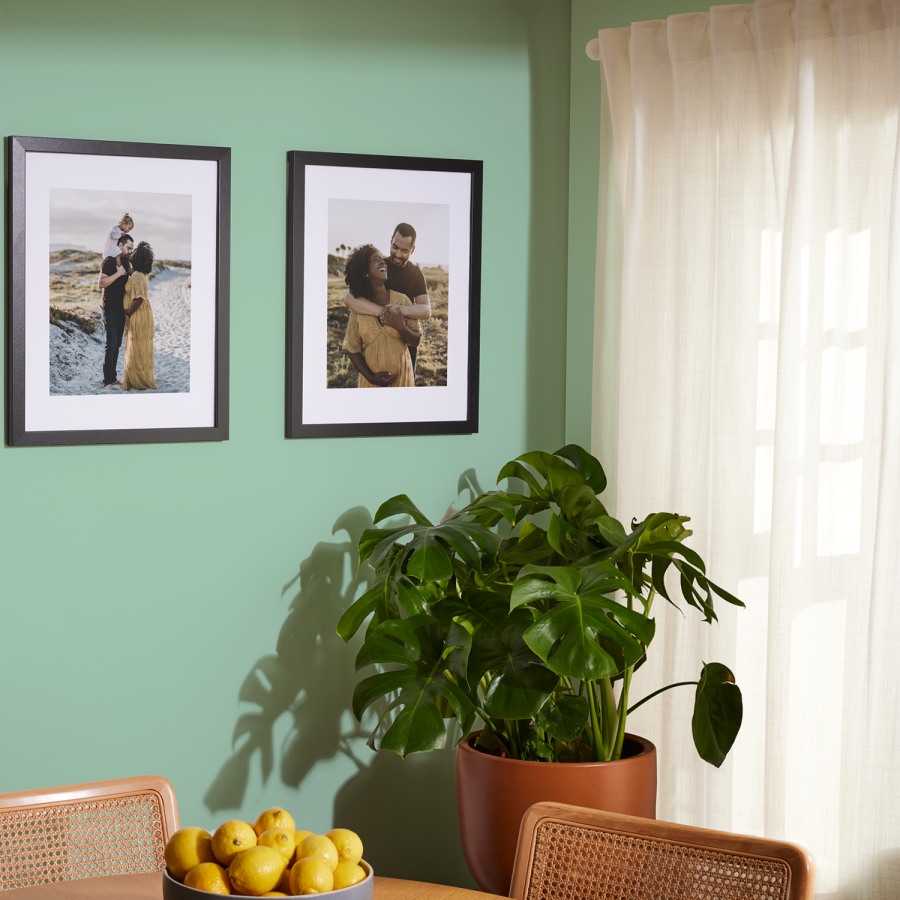 A pair of black framed prints with white borders hung side-by-side on a wall, both featuring family photos. 