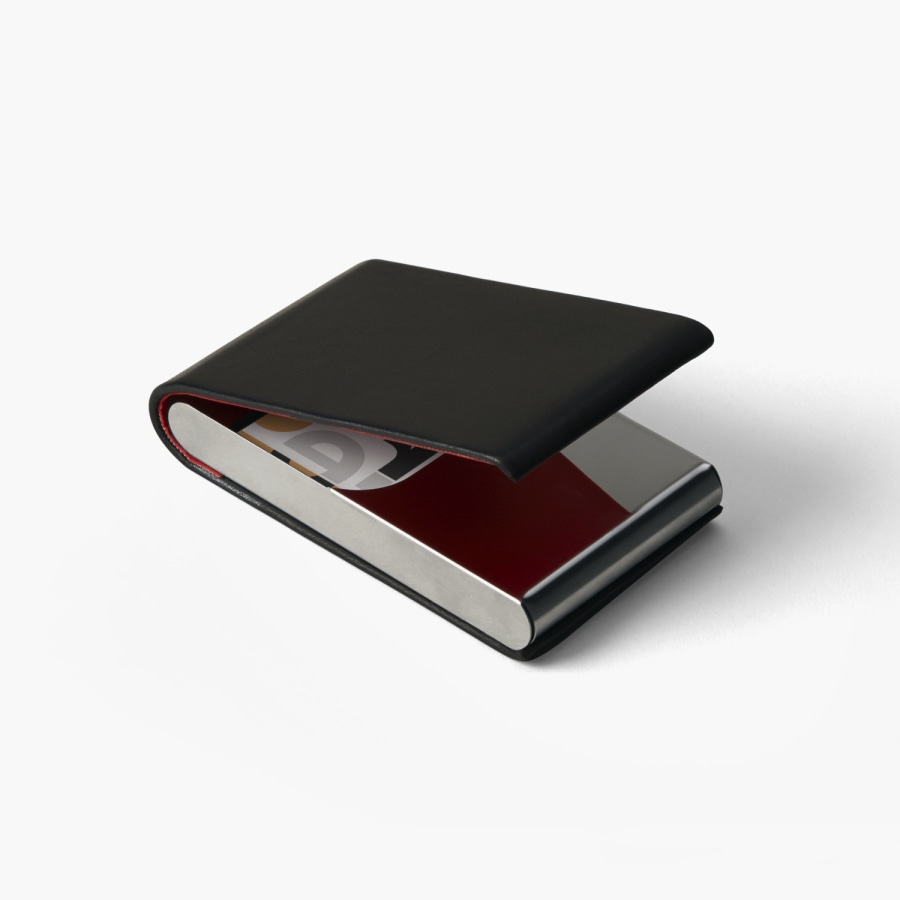 A black leather vertical business card holder slightly opened showing the cards inside. 