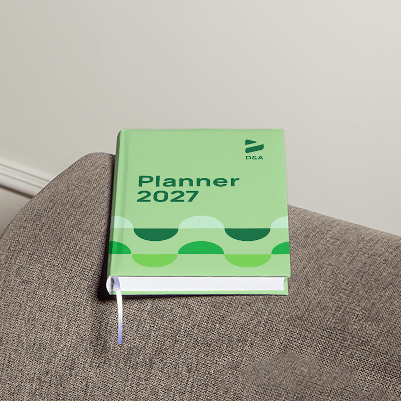 A hardcover diary on top of a sofa’s armrest promoting a design company.