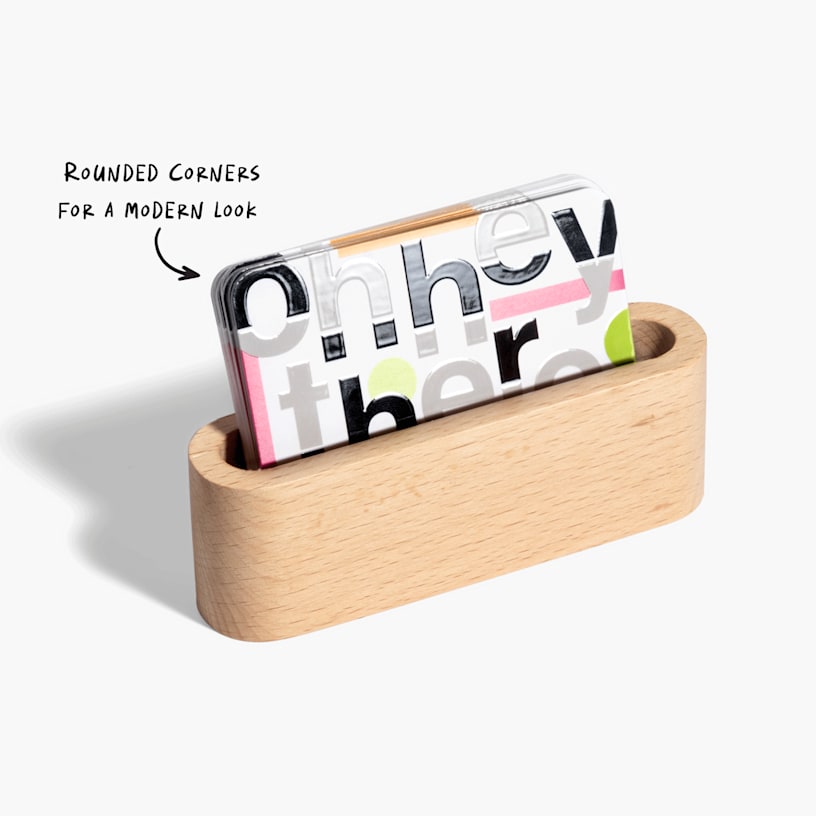 A stack of spot UV business cards displayed in a wooden holder, featuring rounded corners.