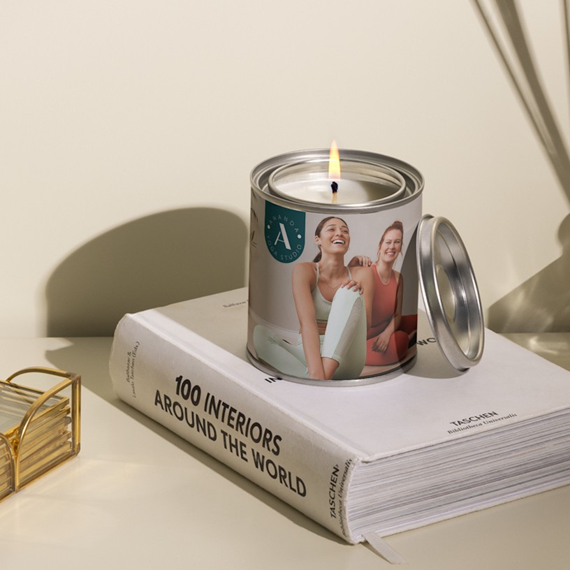 A custom candle personalised for a yoga studio featuring a business logo and a photo of women in yoga attire. 