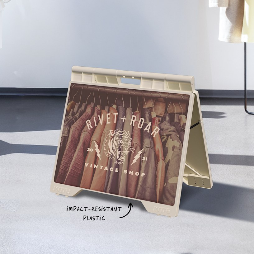 A white, small A-frame promoting a vintage apparel shop, displayed outdoors. 