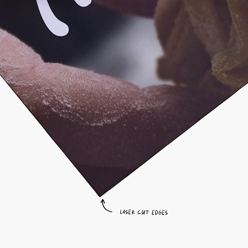 A closeup of one corner of the fabric poster. An arrow points to the laser cut edges.