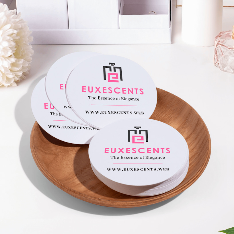 Circle name cards promoting a perfume shop, displayed on a counter.