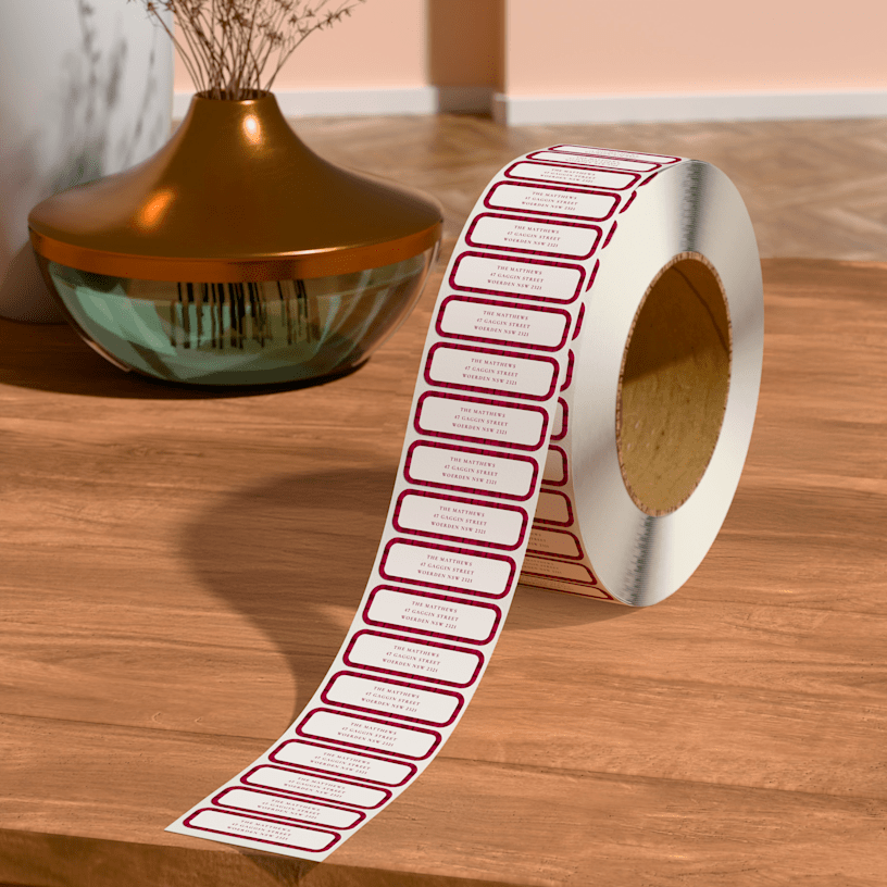 A personalised return address roll label placed on a table, next to a vase.