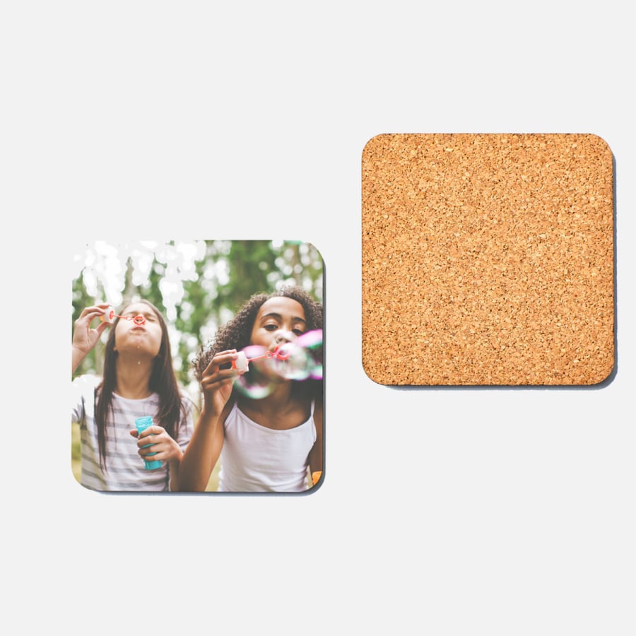 The front and back view of a photo coaster. The front features two girls blowing bubbles and the back displays the coaster's cork material.
