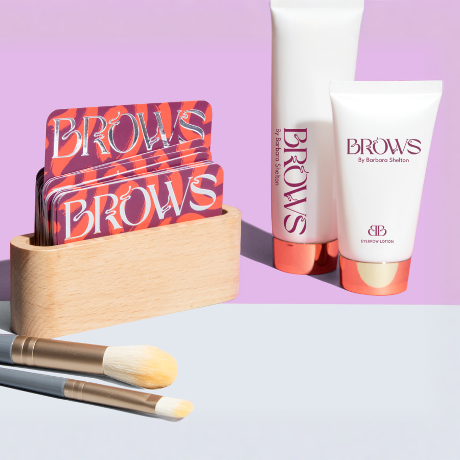 Raised foil business cards promoting beauty products, in a wooden business card holder.