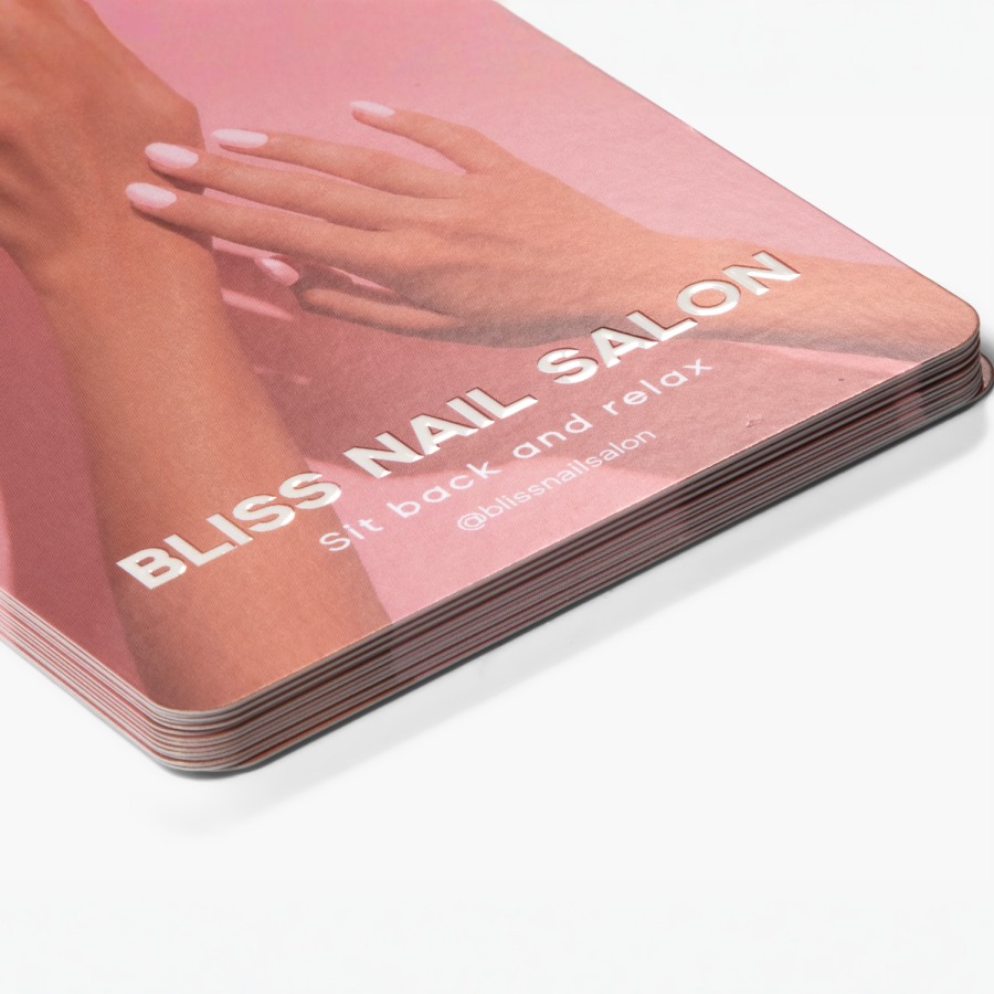 A small stack of embossed gloss rack cards, promoting a nail salon.