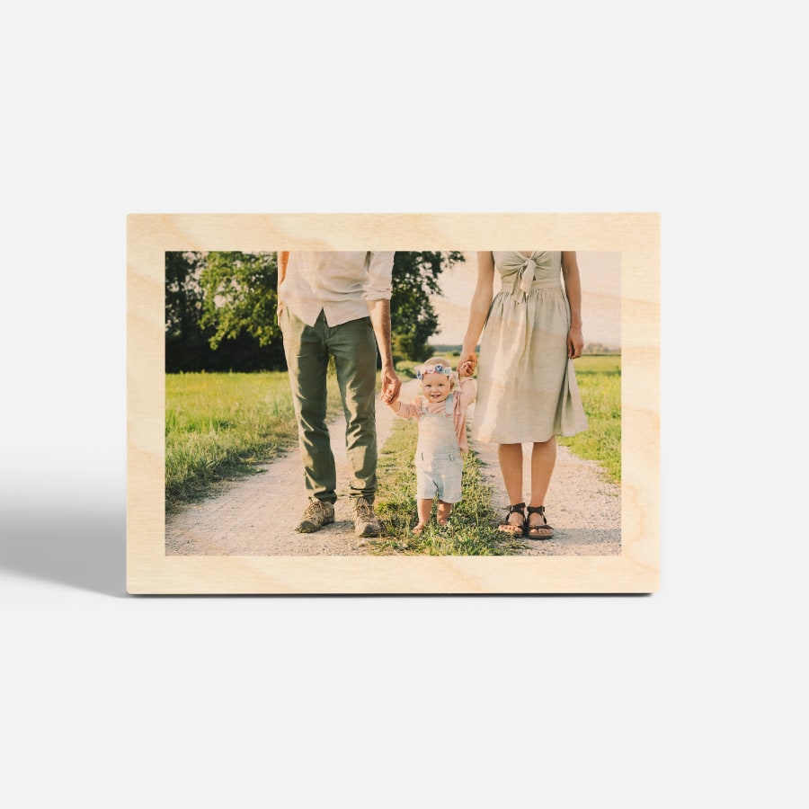 A tabletop wood print featuring a photo of a couple walking hand in hand with their toddler. 