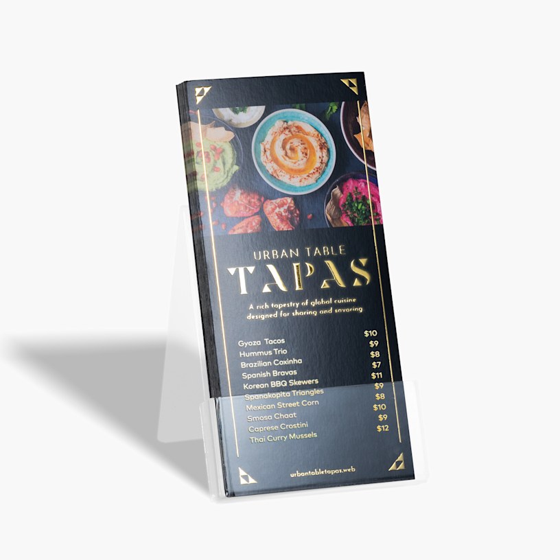 A stack of gold embossed foil rack cards for a restaurant menu, in a plastic holder.