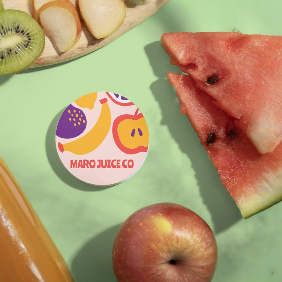 A stack of circle business cards for a juice company. The circle cards are sitting next to fresh fruits and a bottle of juice.