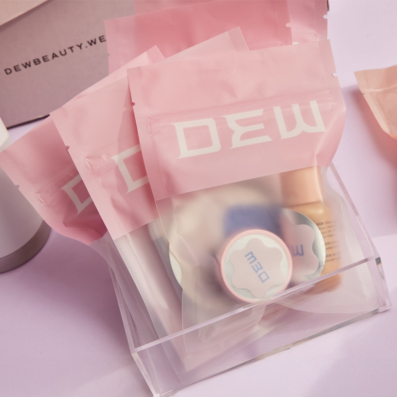 Flat pouches with clear plastic displaying small cosmetics inside.