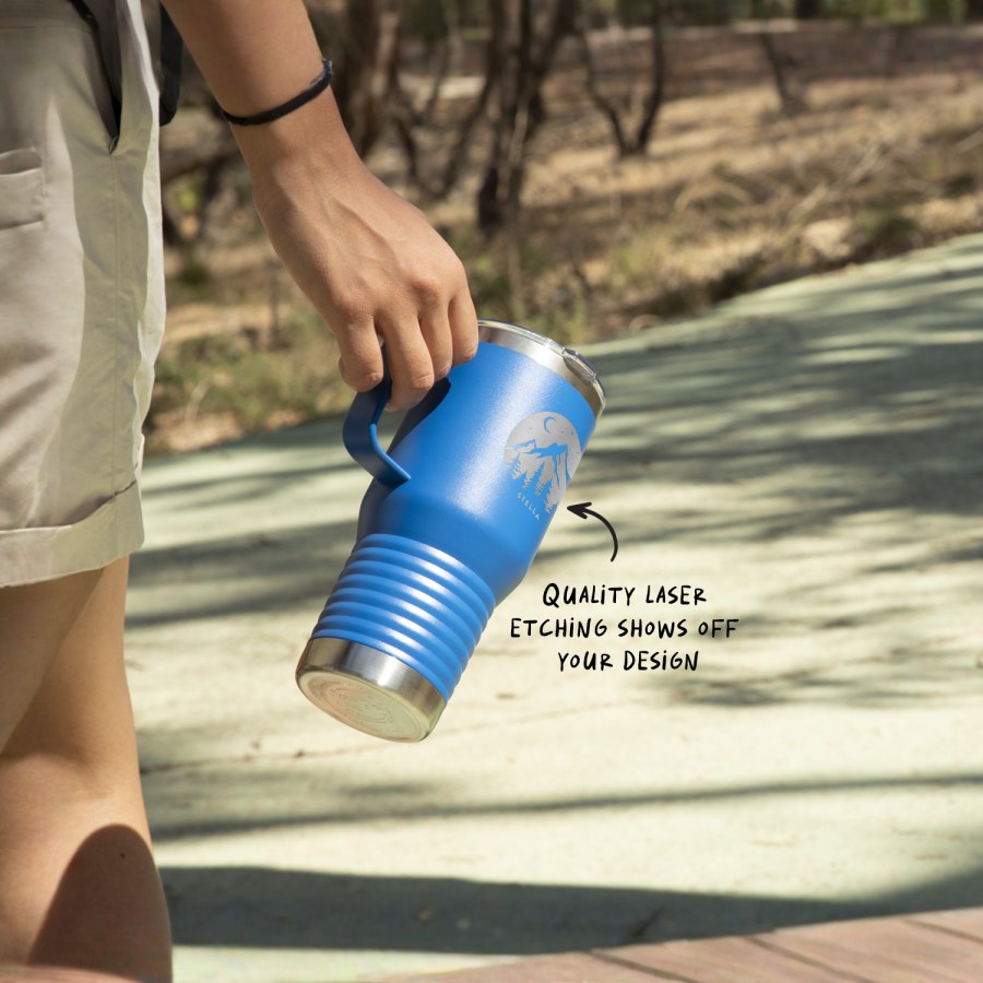 A blue custom travel mug being carried on a hiking excursion. 