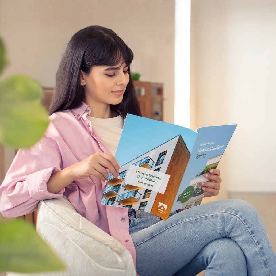 A woman sitting and reading a perfect-bound booklet for a real estate agency.
