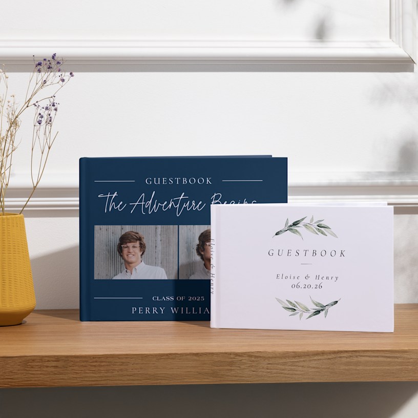 Two custom guest books displayed on a table, one personalized for a graduation party and the other for a wedding. 