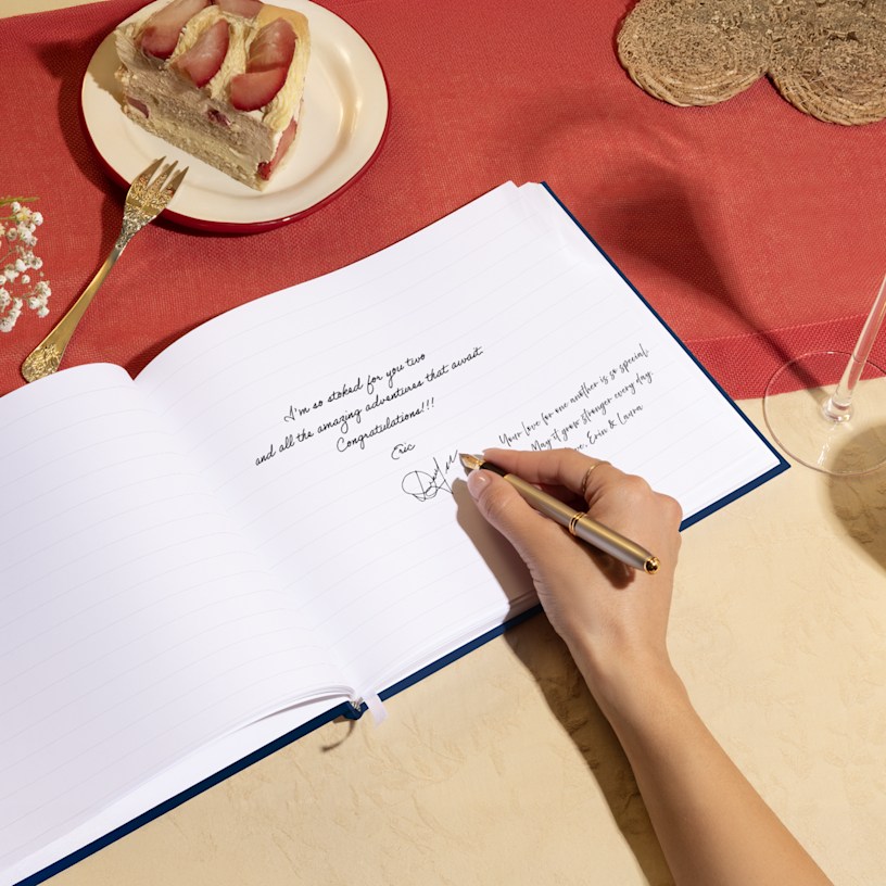 A hand signing an open guest book. 