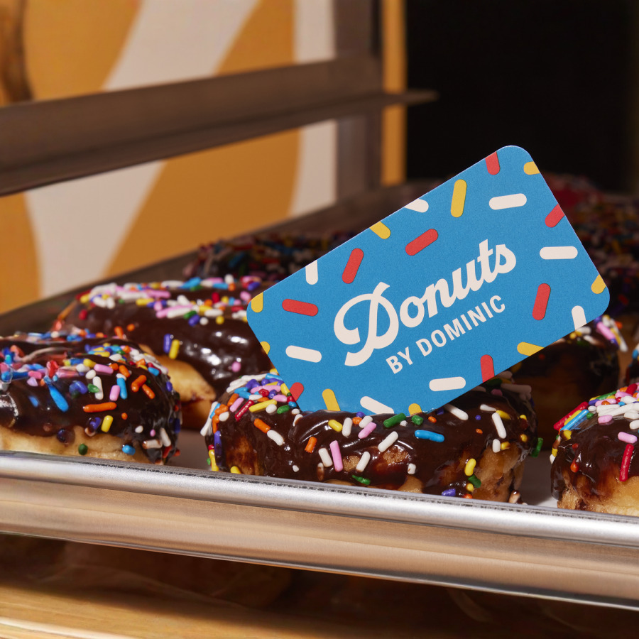 A playful blue business card resting on a tray of donuts.