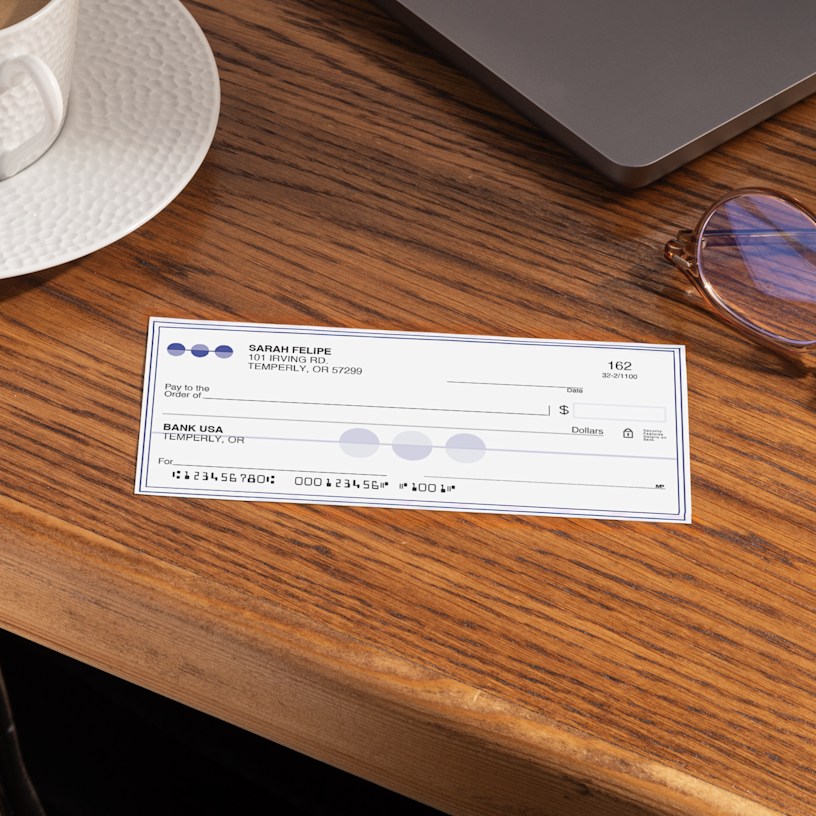 A single wallet check on a desk next to a laptop and other office supplies.