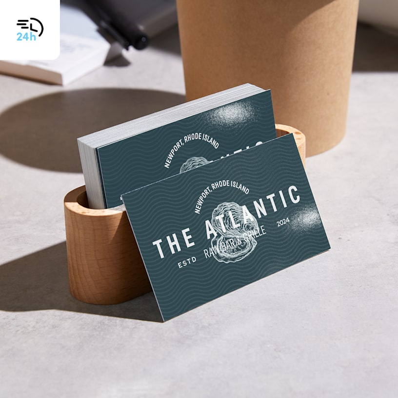 A stack of business cards from a restaurant in a card holder, with a 24-hour delivery icon in the corner.