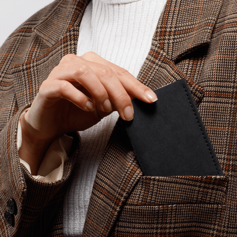 A person holding a slim black business card holder.